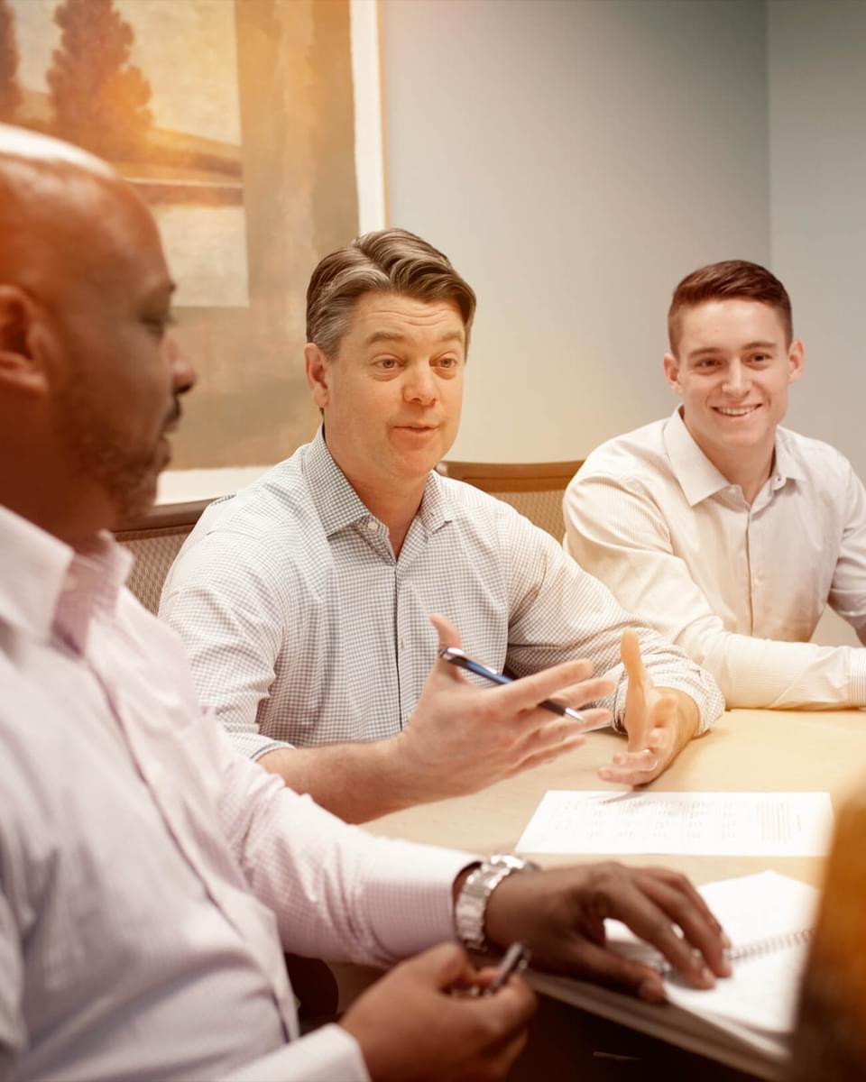 Three people talking in a board room.